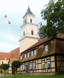 Fachwerkhaus und Kirche mit fliegenden Schwalben